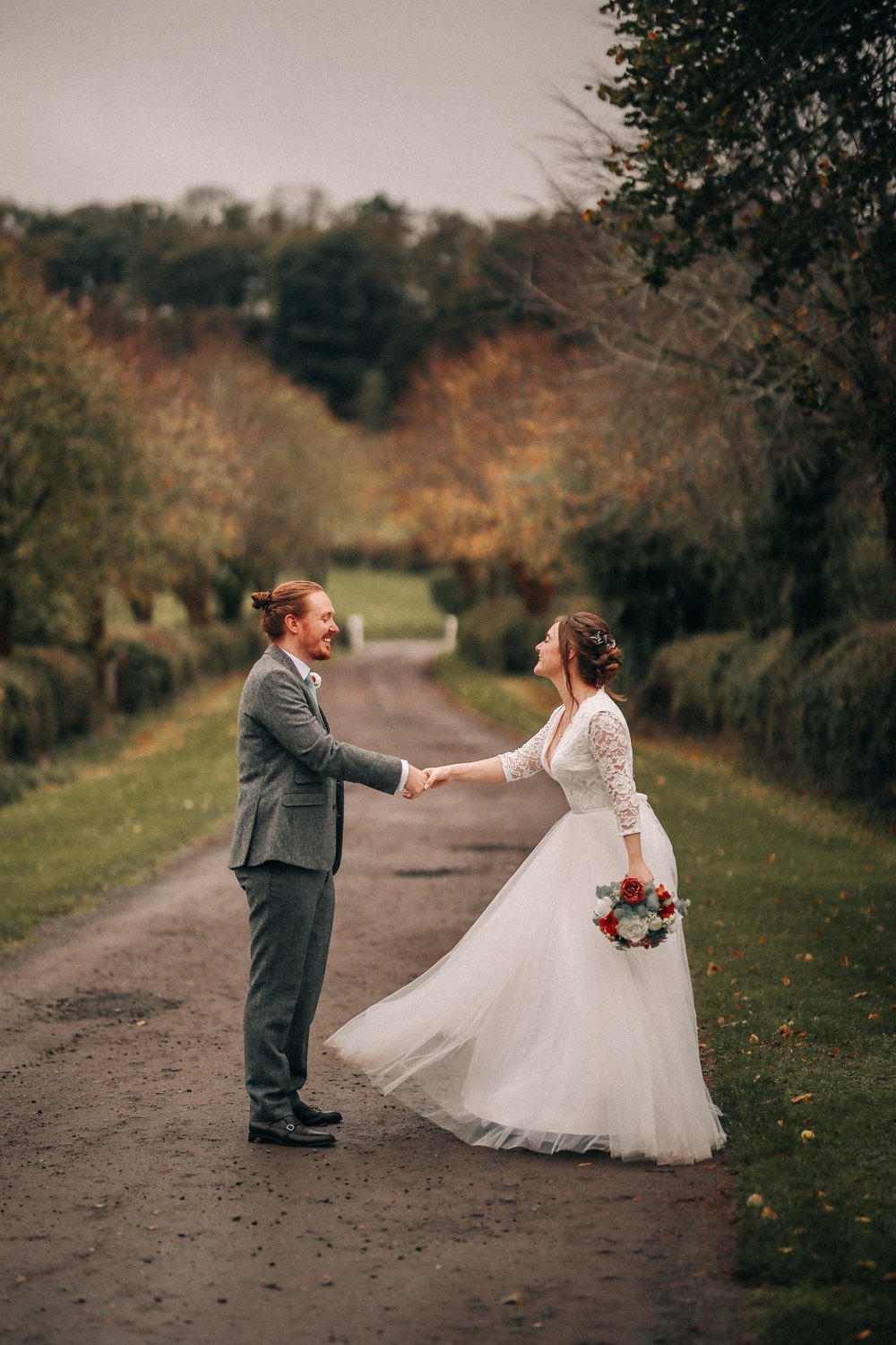 Real Lace & Love bride in a long sleeve lace wedding dress on a country lane lined with autumn trees