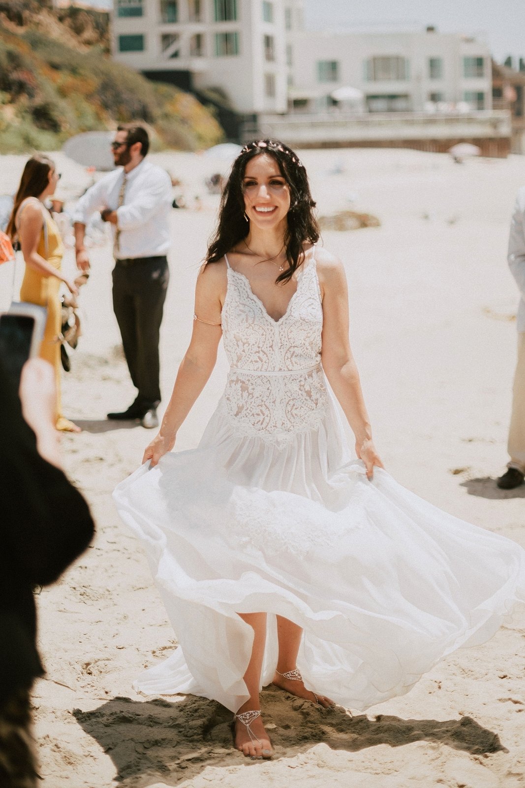 Real bride in a flowing boho wedding dress walking on the beach at an outdoor summer wedding