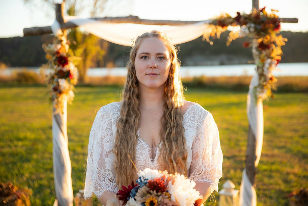 Bride in a boho lace wedding dress holding a bouquet during a sunset bridal portrait.