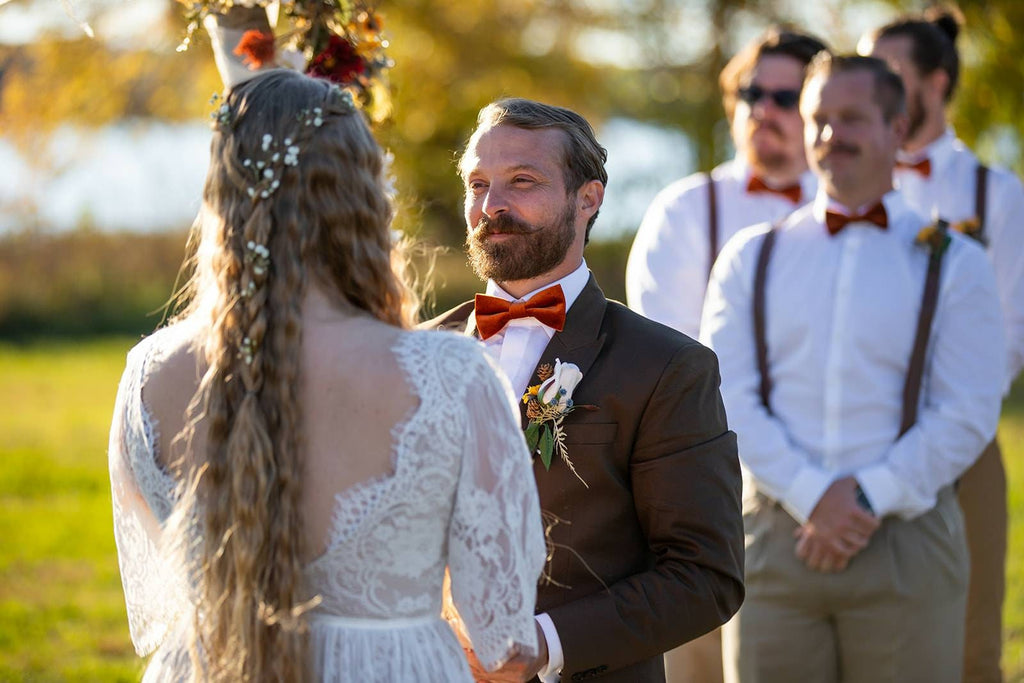 Boho bride and groom standing together during an intimate outdoor wedding ceremony.