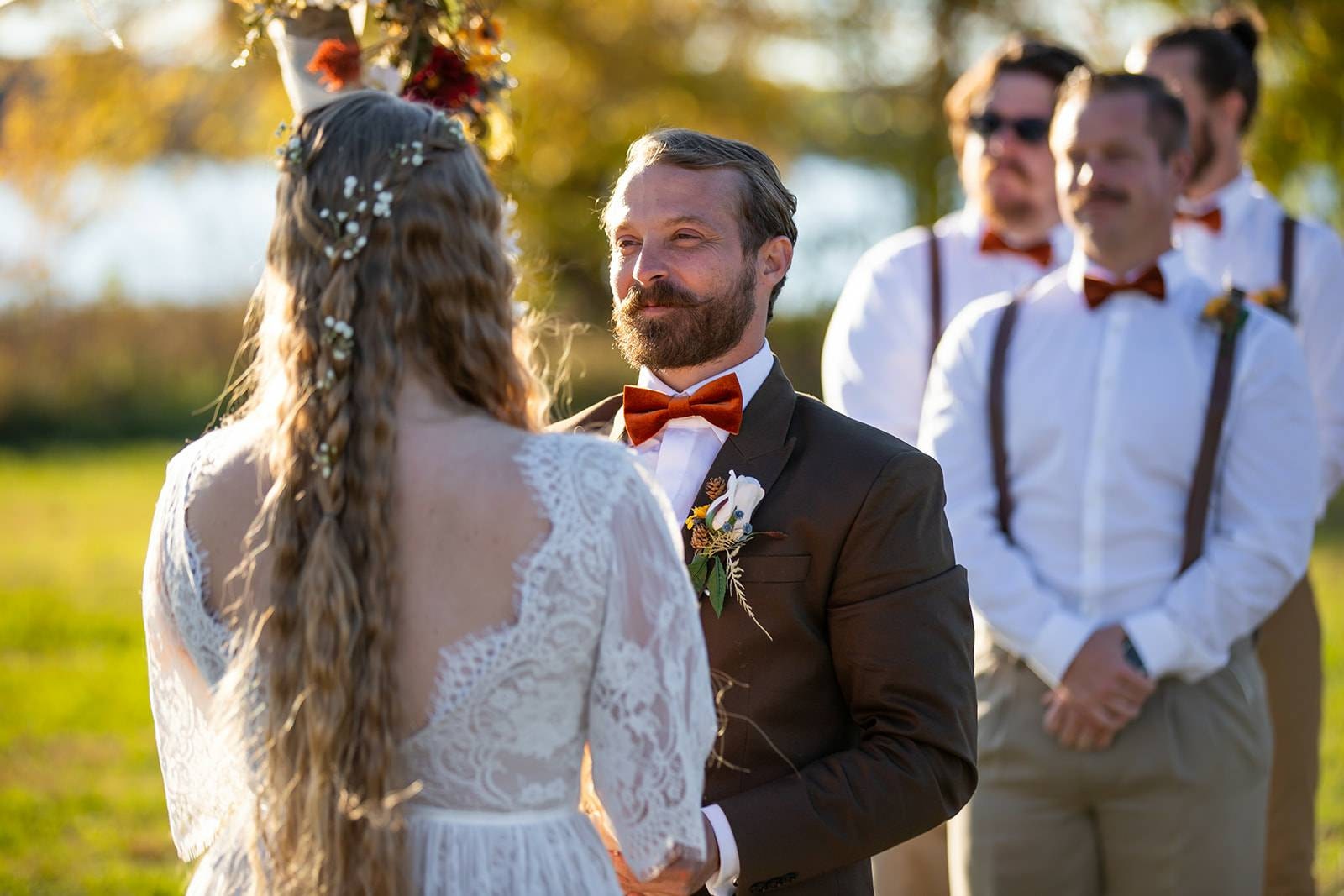 Boho bride and groom standing together during an intimate outdoor wedding ceremony.