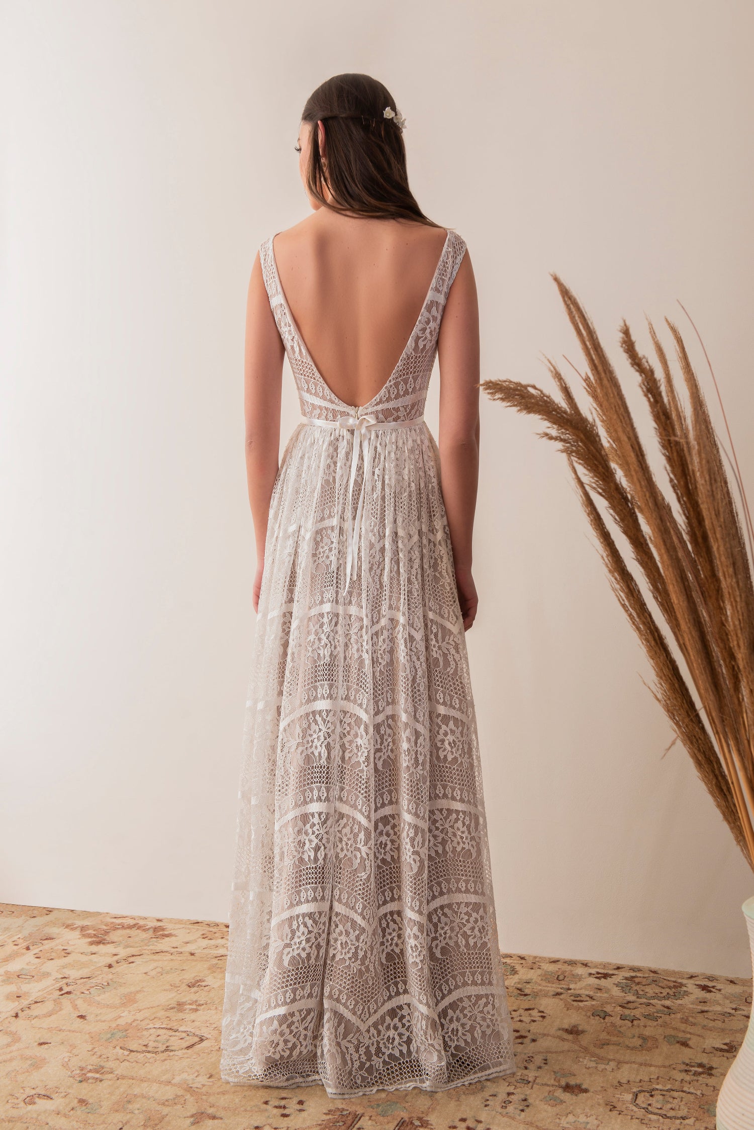 Side back view of a boho lace bridal gown with flowing skirt