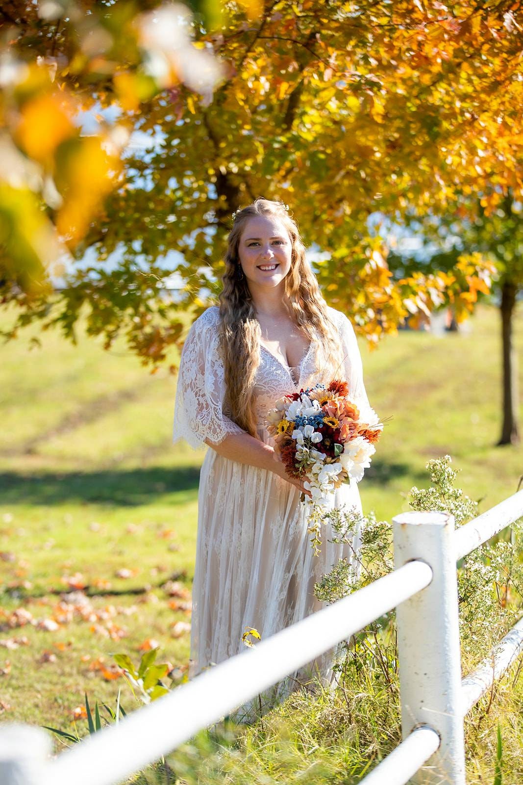 Bride in a boho lace wedding dress holding a bouquet during an outdoor bridal portrait.