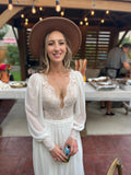 Bride wearing a boho lace long sleeve wedding dress with a wide brim hat.