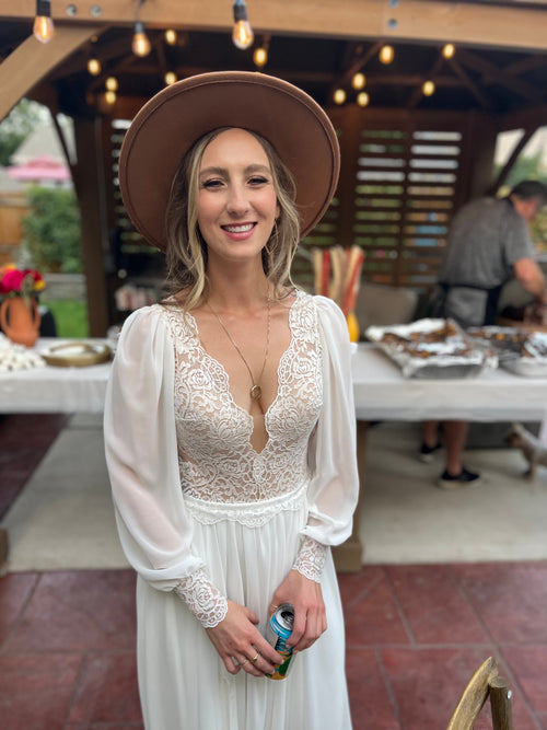 Bride wearing a boho lace long sleeve wedding dress with a wide brim hat.
