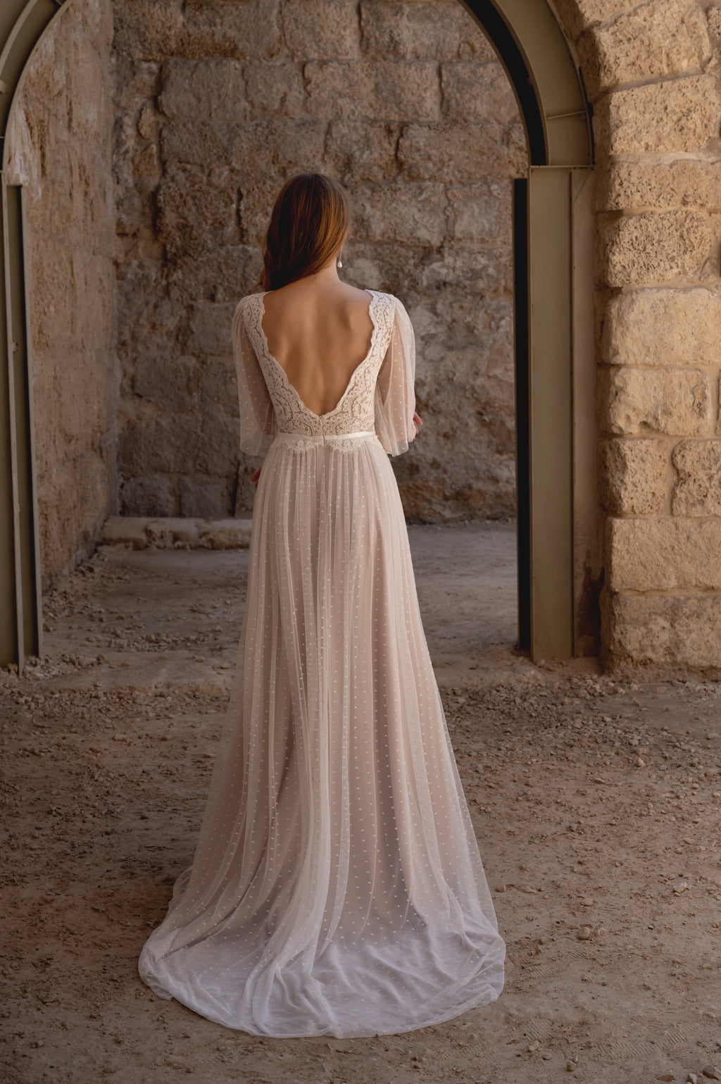 Back view of a boho lace wedding dress with a low back and flowing train