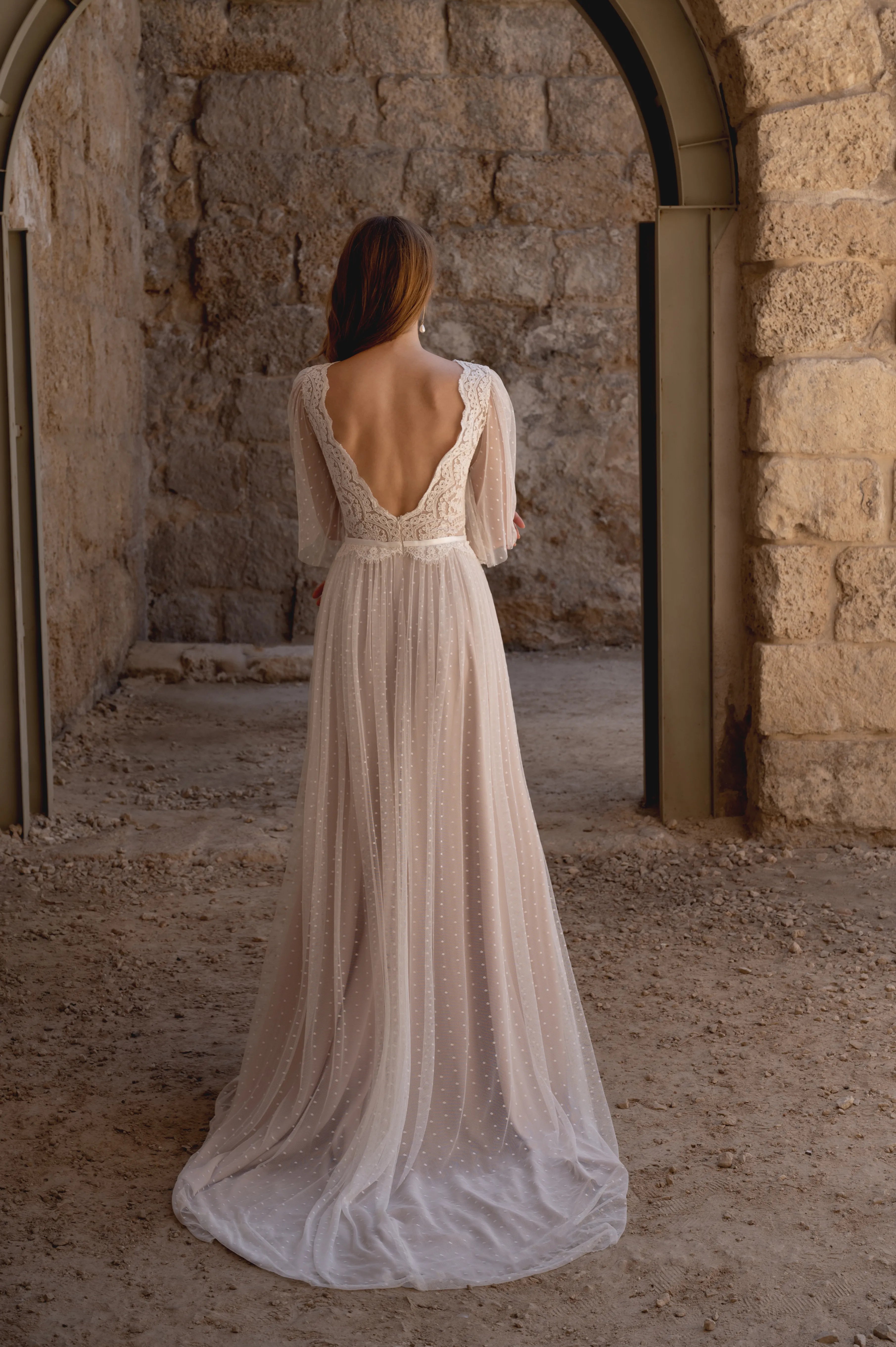 Back view of a boho lace wedding dress with a low back and flowing train