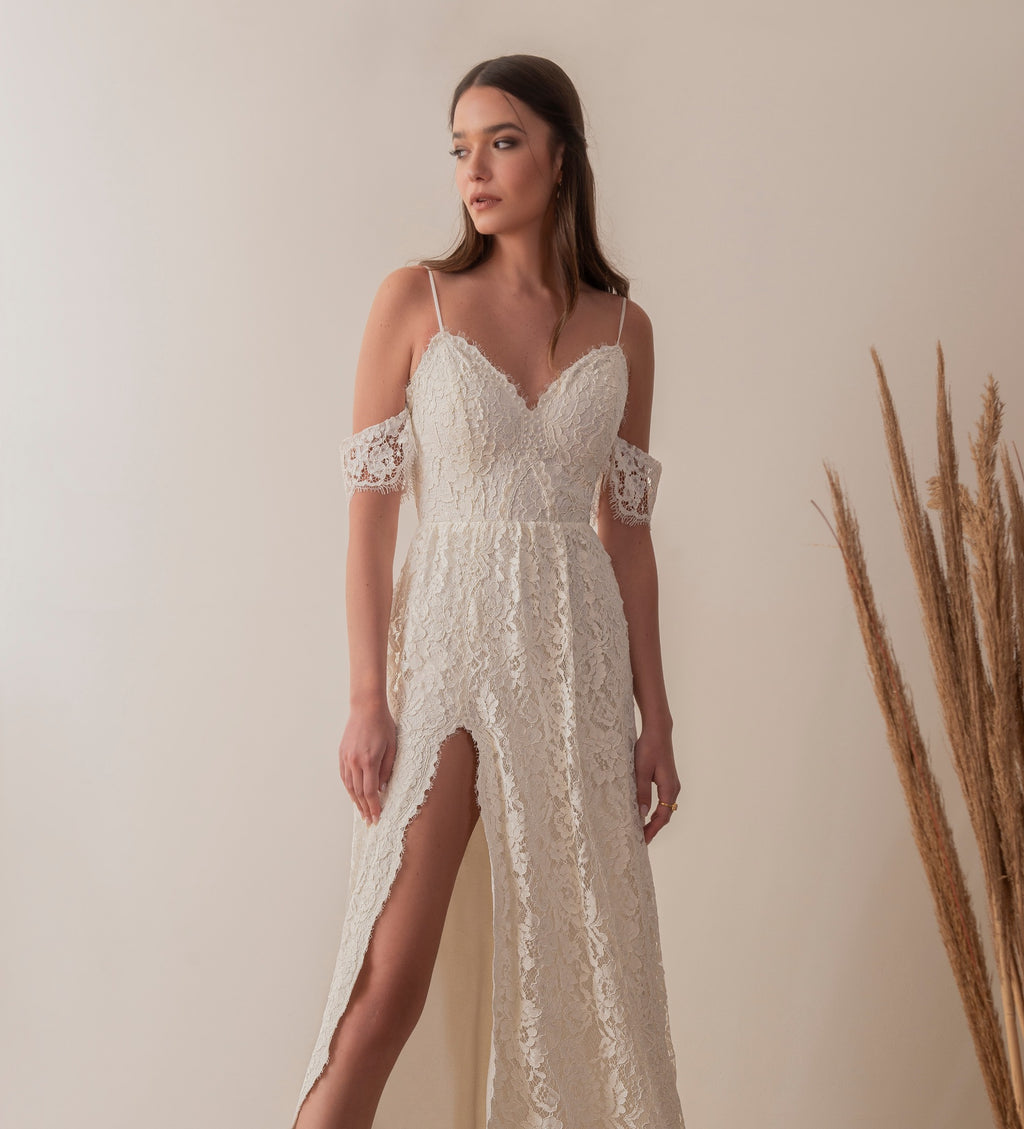 Bride wearing a boho lace wedding dress with detachable sleeves and front slit