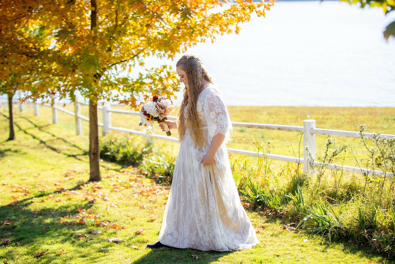 Bride wearing a boho lace wedding dress walking through a vineyard on her wedding day.