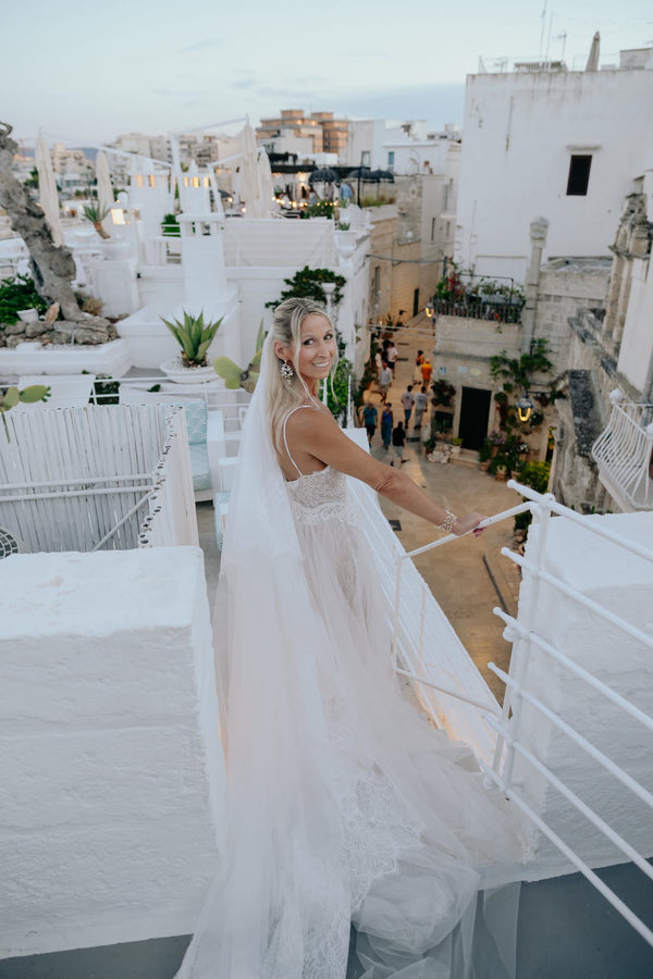 Real Lace & Love bride Niki in her lace wedding dress and long veil on a white rooftop terrace