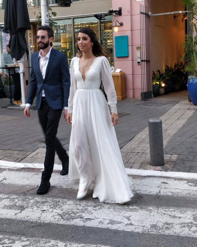 Ingrid Gown, bride in a long sleeve French lace wedding dress walking with her groom on a city street