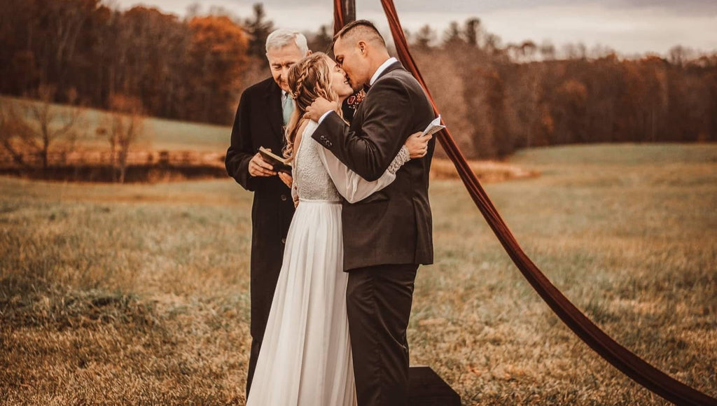 Bride wearing a boho lace wedding gown during an intimate outdoor wedding ceremony.