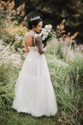 Real bride wearing a boho lace wedding dress with tulle skirt in a garden