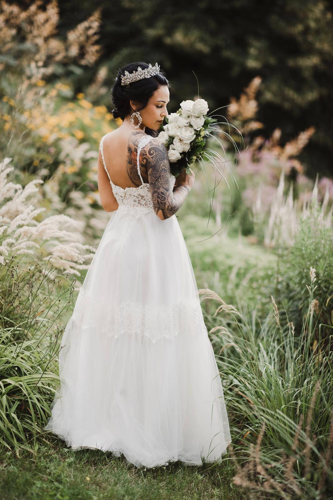 Real bride wearing a boho lace wedding dress with tulle skirt in a garden