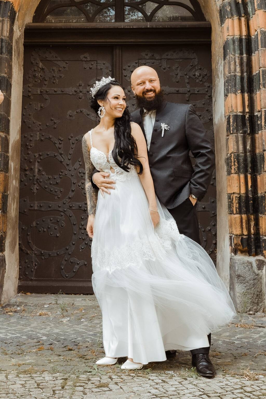 Bride wearing a boho wedding dress with lace bodice at a stone doorway