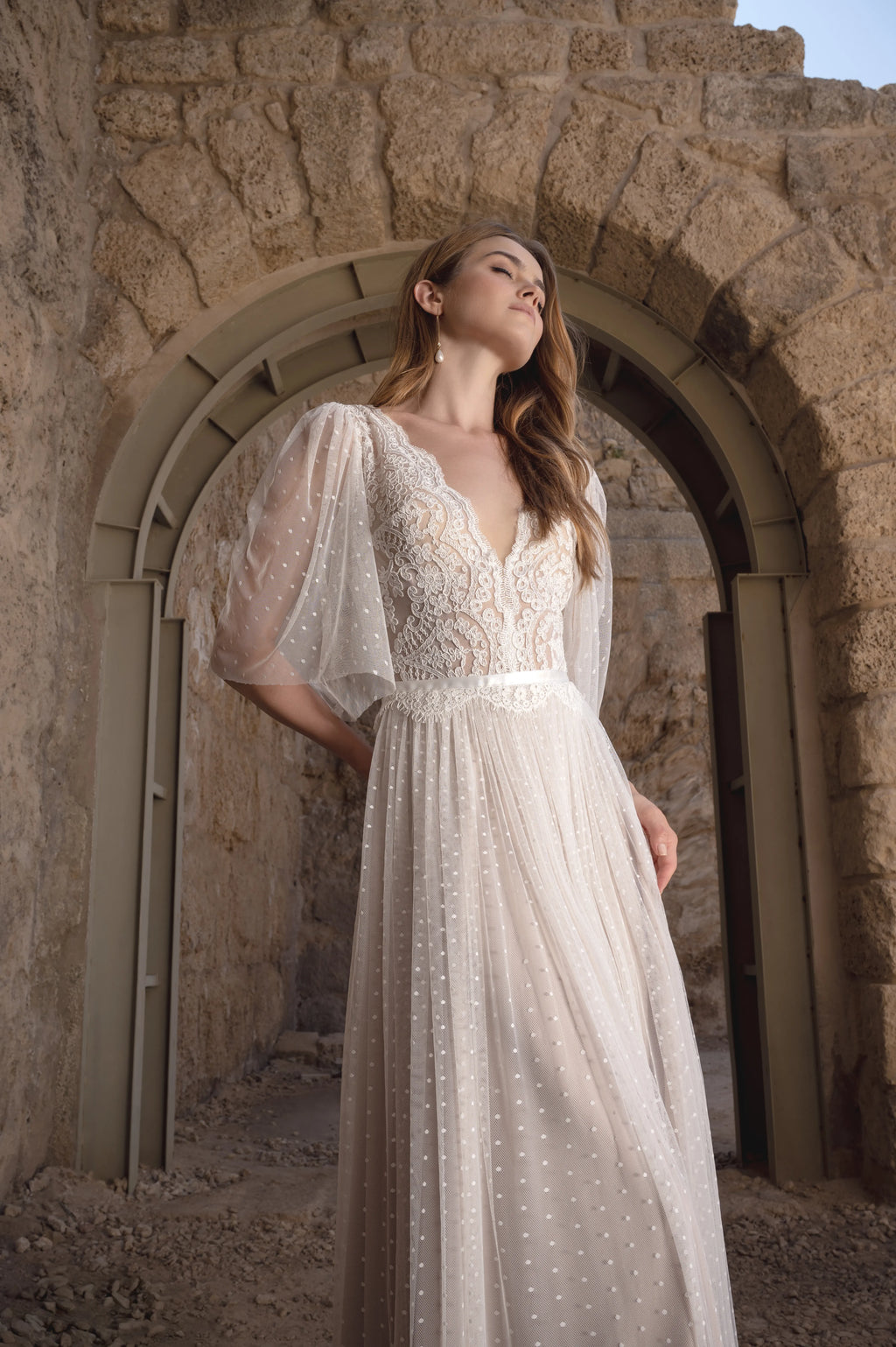 Romantic boho wedding dress with lace bodice and flowing skirt in a stone venue
