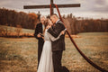 Bride and groom standing beneath a rustic wedding arch during their boho outdoor ceremony.