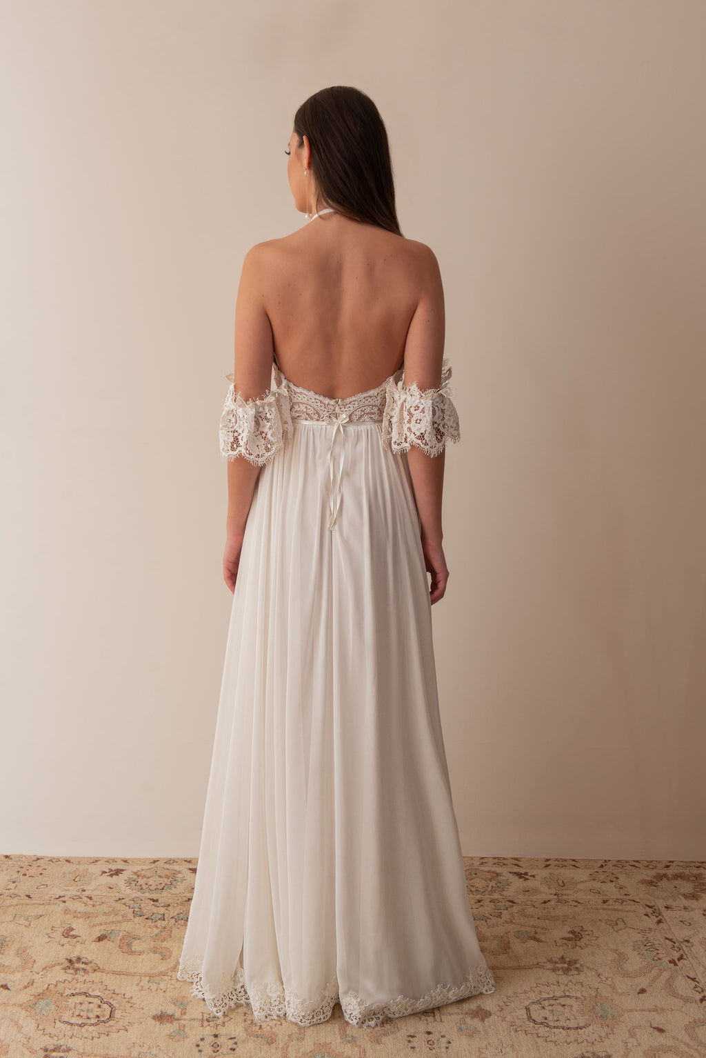 Back view of a boho wedding dress with lace sleeves and flowing skirt