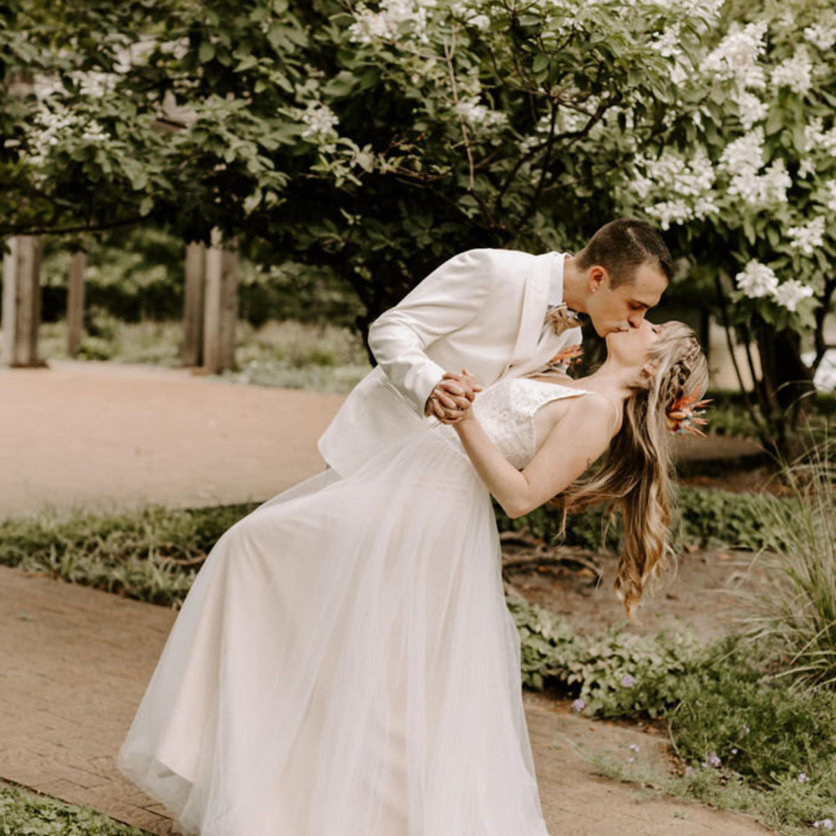 Thea Gown, Lace & Tulle Boho Wedding Dress, Made to Measure, worn by a bride in a wedding photograph with her partner